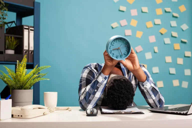 como vencer a procrastinacao definitivamente homem segurando relogio azul na mesa com post its para